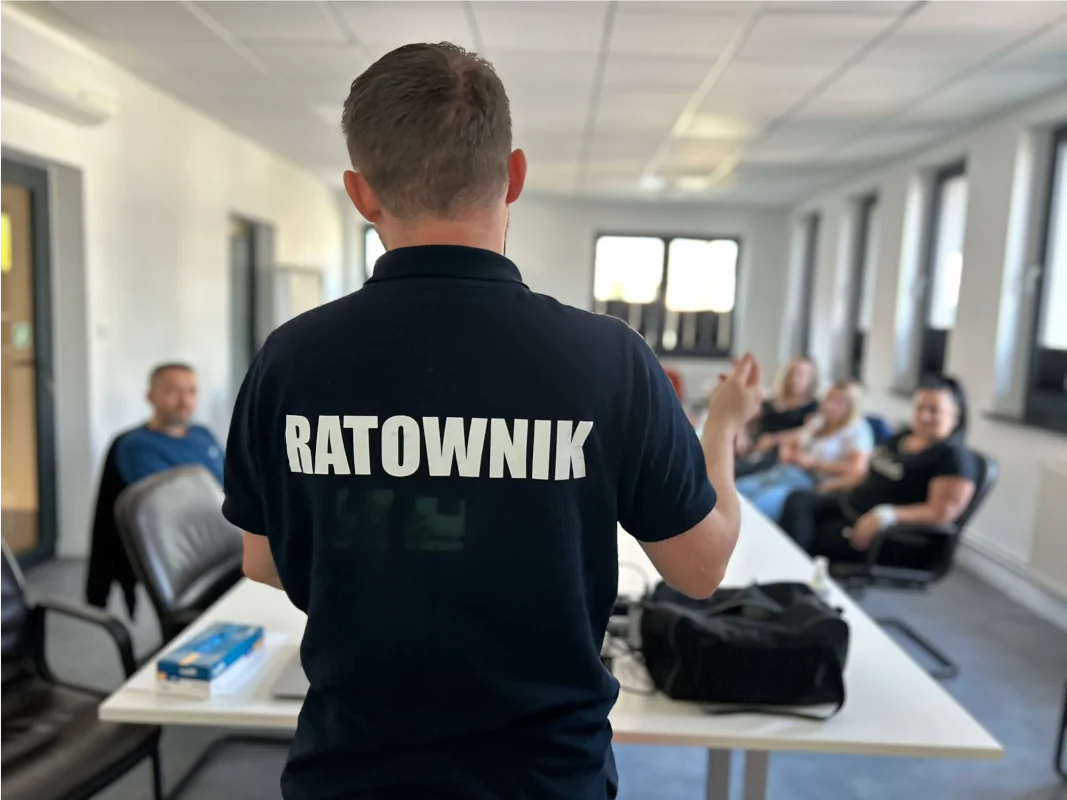 Instruktor szkoli grupę z udzielania pierwszej pomocy